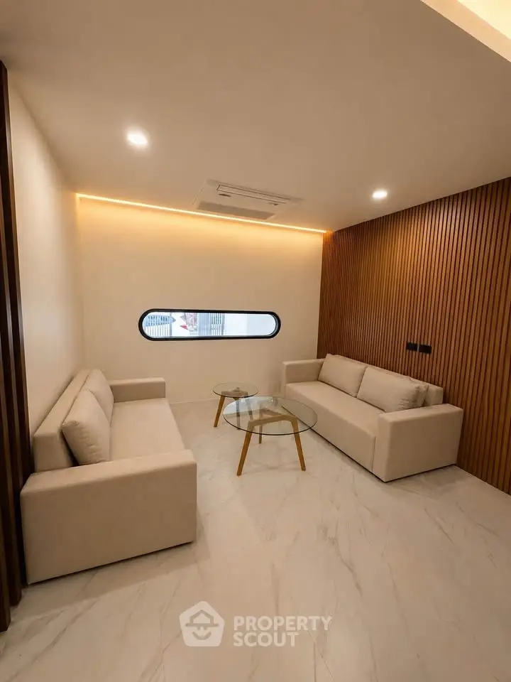 Modern living room with sleek design, featuring two beige sofas and a glass coffee table.