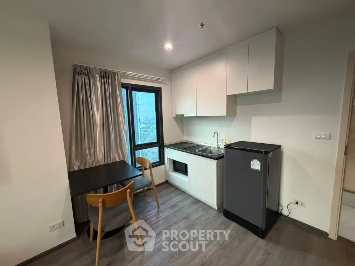 Modern kitchen with sleek cabinets and dining area in cozy apartment