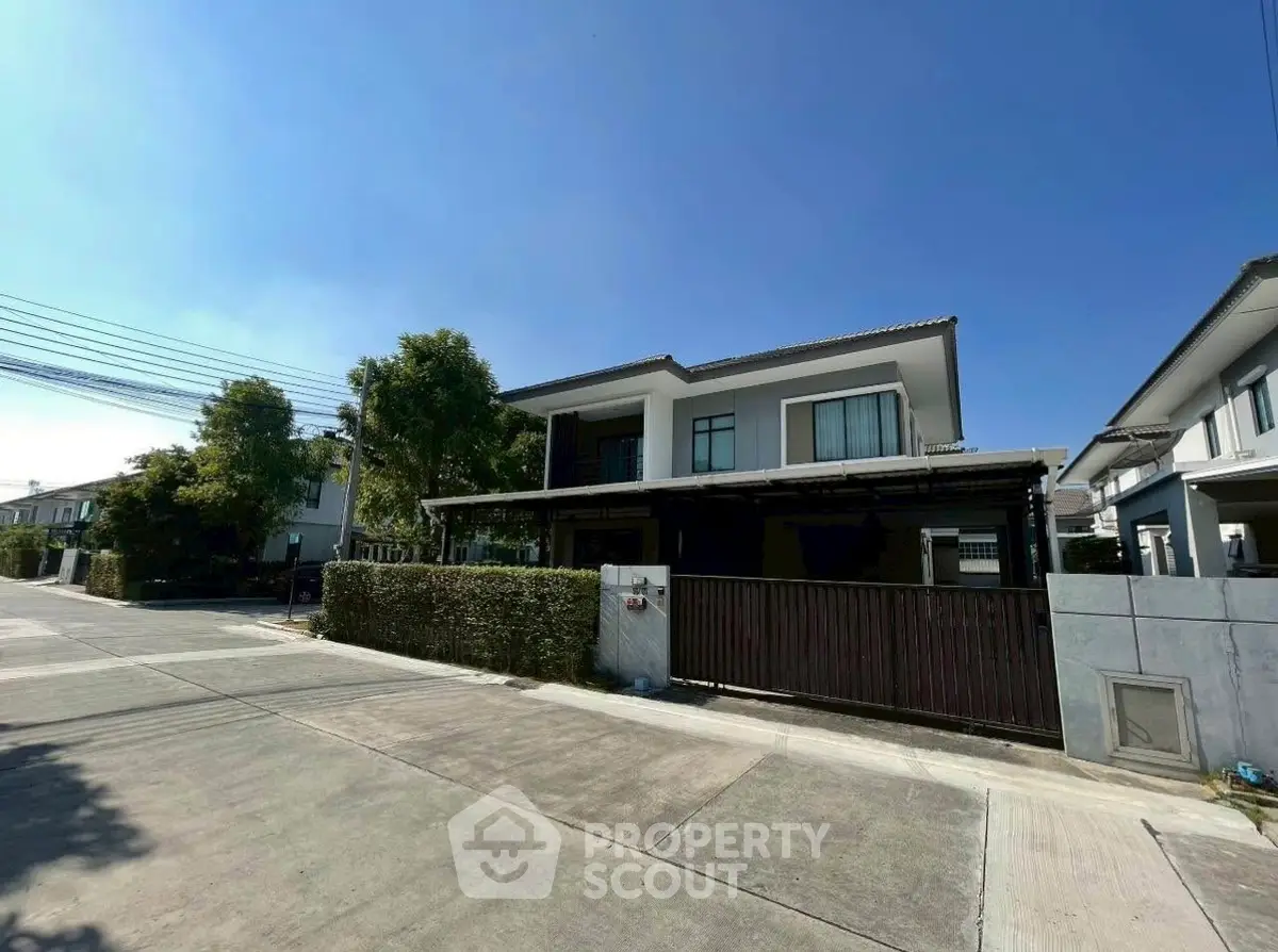 Modern two-story house with a spacious driveway and lush greenery in a serene neighborhood.
