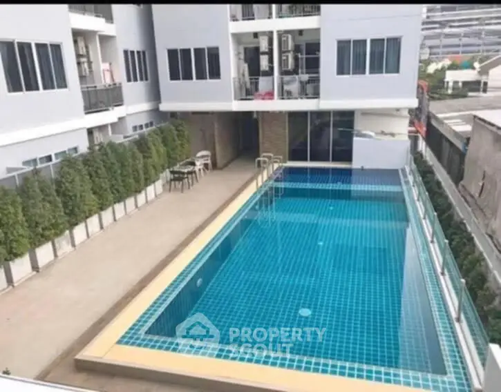 Modern apartment complex with a pristine outdoor swimming pool and spacious deck area.