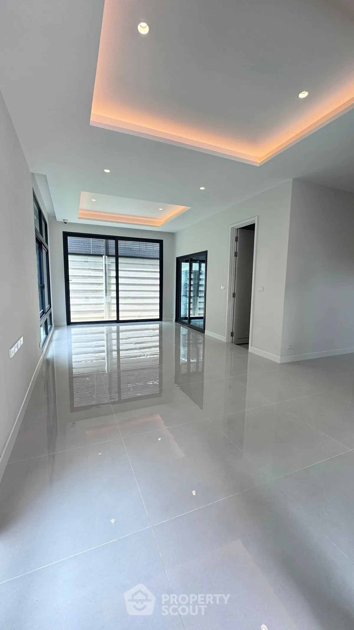 Spacious modern living room with sleek tile flooring and ambient lighting