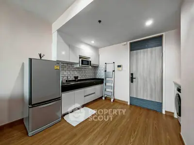Modern kitchen with sleek appliances and wooden flooring in a stylish apartment.