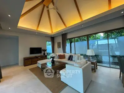 Luxurious living room with high ceiling and modern decor, featuring large windows and elegant lighting.