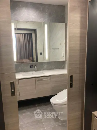 Modern bathroom with sleek design, featuring a large mirror, elegant vanity, and contemporary fixtures.