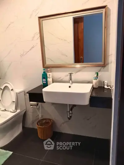 Modern bathroom with sleek sink and toilet, featuring elegant marble tiles.