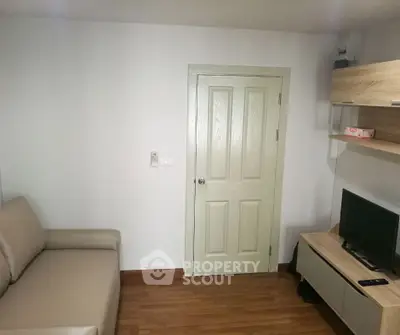 Cozy living room with beige sofa, wall-mounted TV, and wooden flooring for modern comfort.