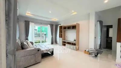 Spacious living room with modern sofa and entertainment unit, featuring large windows and elegant curtains.