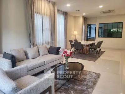 Spacious modern living room with elegant dining area, featuring stylish furniture and large windows for natural light.