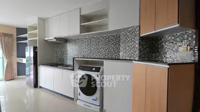 Modern kitchen with sleek cabinetry, mosaic backsplash, and built-in appliances including washing machine.