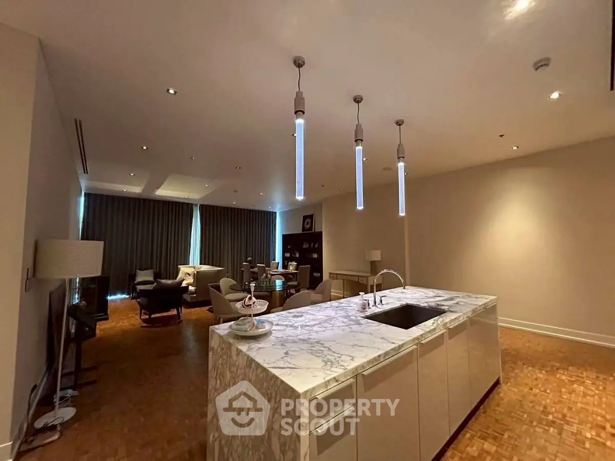 Luxurious open-plan living room with elegant marble kitchen island and modern lighting.