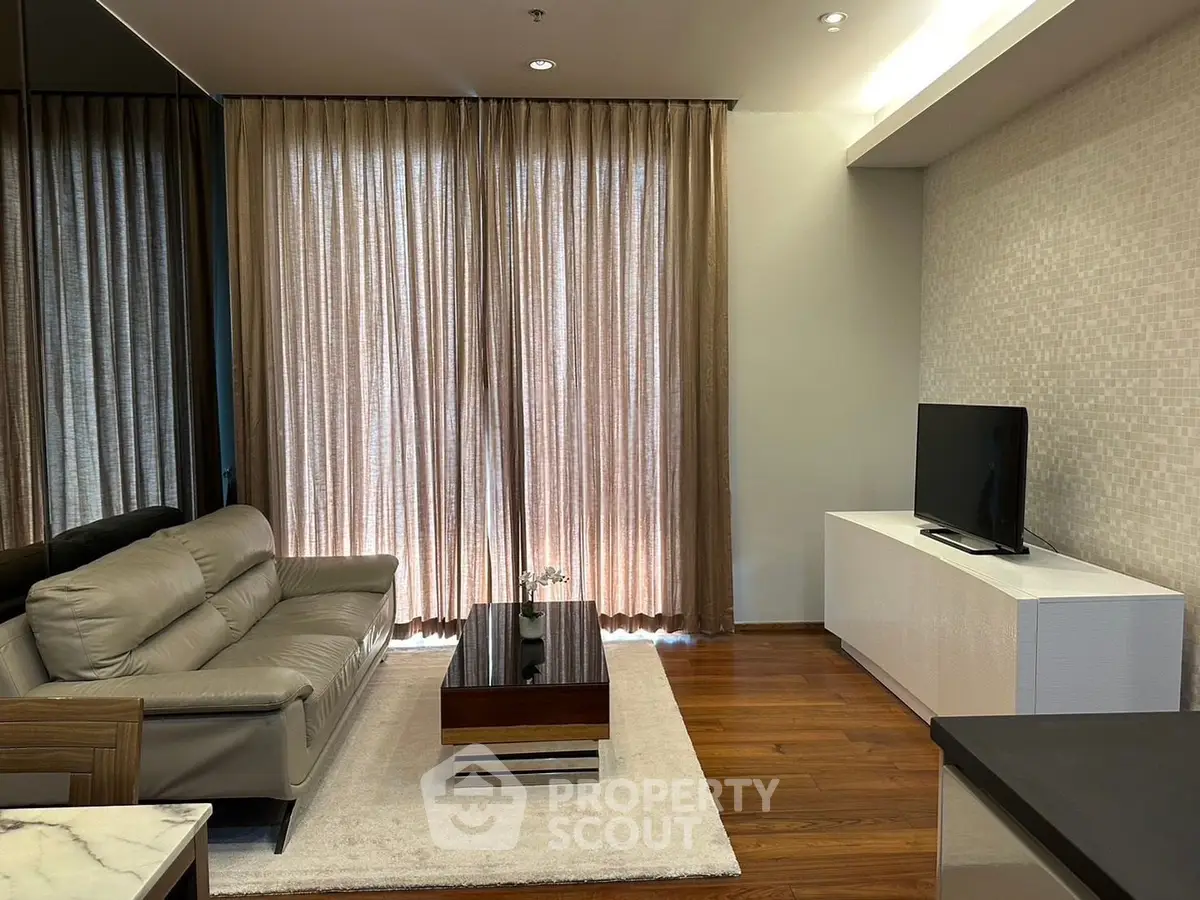Modern living room with elegant decor, featuring a sleek sofa, stylish coffee table, and a flat-screen TV.