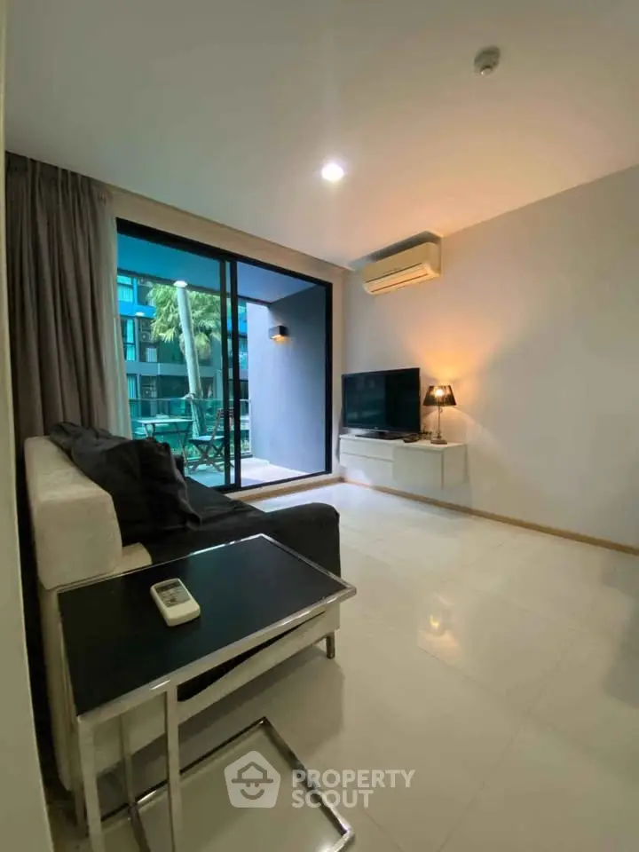 Modern living room with balcony view, featuring sleek furniture and natural light.