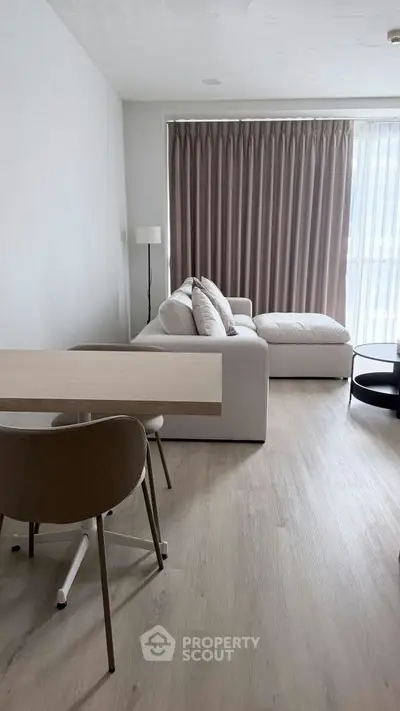 Modern living room with elegant decor and natural light, featuring a cozy sofa and stylish dining area.