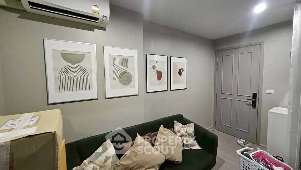 Cozy living room with modern art, green sofa, and air conditioning in a stylish apartment.