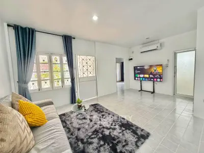 Spacious living room with modern decor, featuring a cozy sofa, stylish rug, and wall-mounted TV.