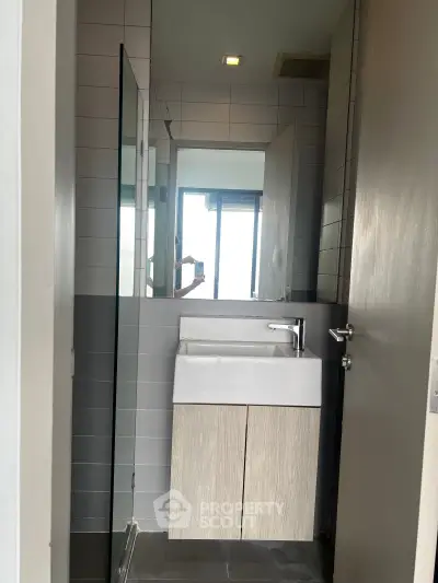 Modern compact bathroom with sleek sink and mirror in contemporary apartment.