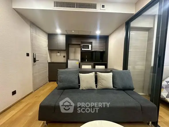 Modern living room with sleek furniture and compact kitchen area, perfect for urban living.