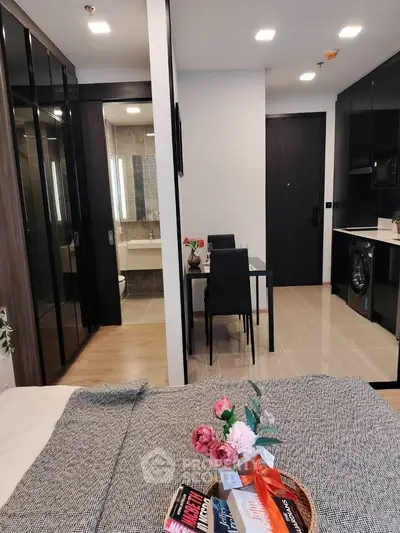 Modern studio apartment with sleek design, featuring a cozy bedroom, dining area, and compact kitchen.