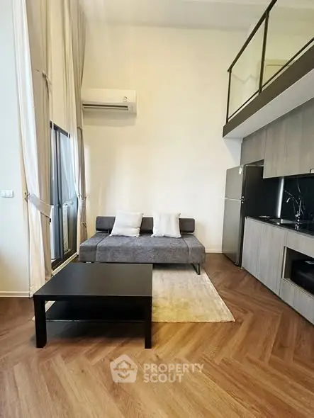 Modern living room with high ceiling and mezzanine, featuring sleek furniture and stylish decor.