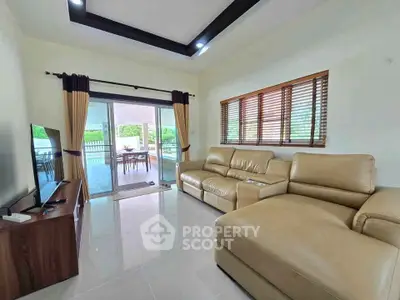 Spacious living room with modern leather sofa and large windows opening to a scenic balcony view.