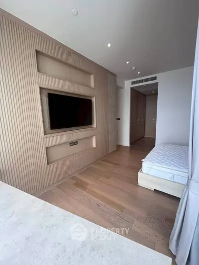 Modern bedroom with wooden flooring and built-in TV unit