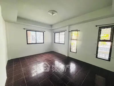 Spacious empty room with tiled floor and large windows for natural light