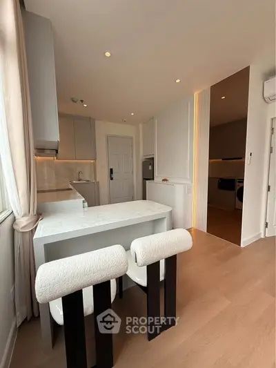 Modern kitchen with sleek design, featuring a breakfast bar and stylish chairs, perfect for contemporary living.