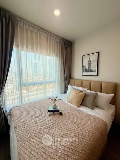 Cozy bedroom with large window and city view, featuring elegant decor and plush bedding.