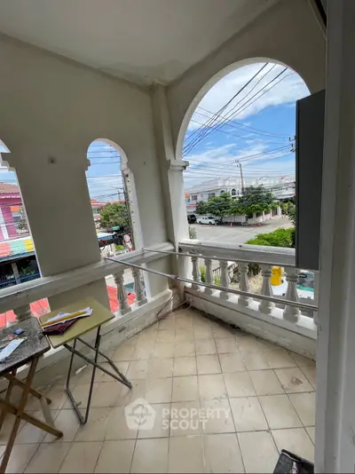 Charming balcony with arched openings offering a vibrant city view, perfect for relaxation.