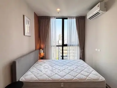 Modern bedroom with large window and city view, featuring a comfortable bed and elegant curtains.