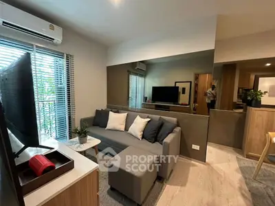 Modern living room with stylish decor and large mirror, featuring a cozy gray sofa and sleek TV setup.