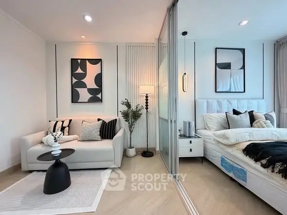 Modern bedroom with stylish decor and cozy seating area, featuring elegant artwork and soft lighting.