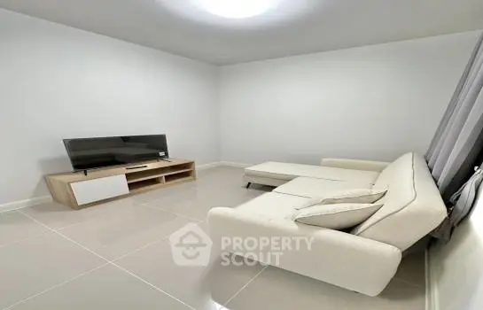 Spacious and modern living room with sleek white sectional sofa and contemporary entertainment unit, featuring glossy tiled flooring and neutral color palette.