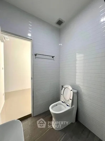 Modern bathroom with sleek white tiles and contemporary toilet design.