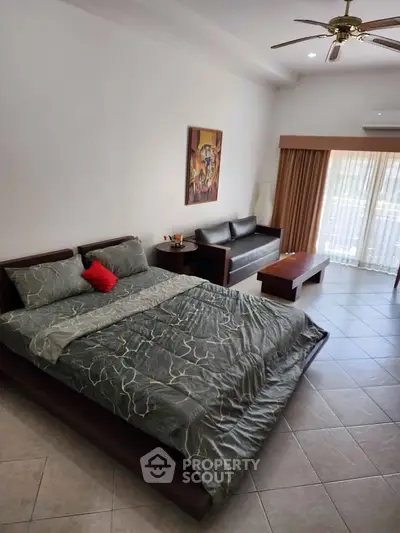 Spacious bedroom with modern decor and natural light, featuring a cozy bed and stylish sofa.