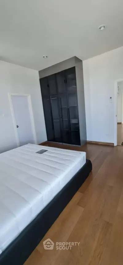 Spacious bedroom with modern black wardrobe and wooden flooring