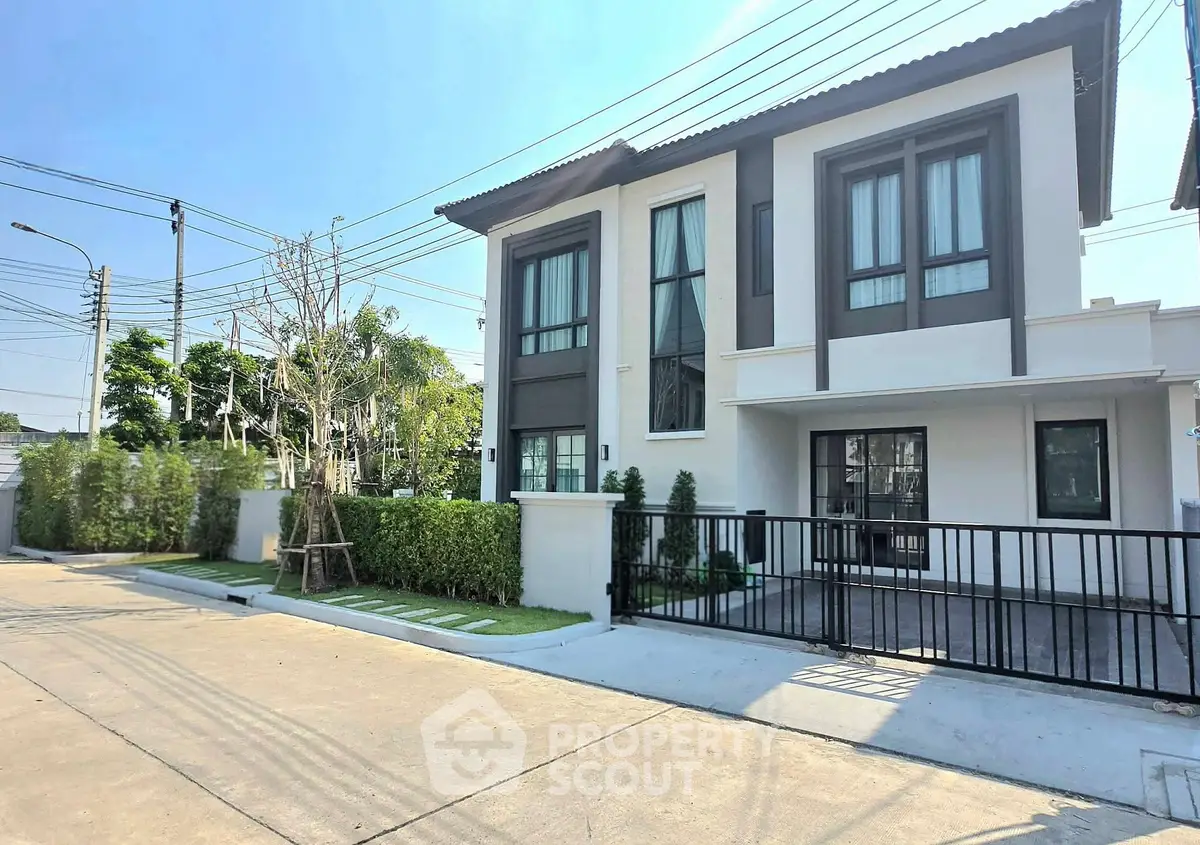 Modern two-story house with sleek design and gated driveway in sunny neighborhood.