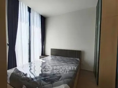 Spacious bedroom with large windows and modern furnishings in a stylish apartment.