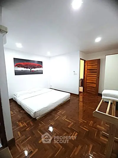 Spacious bedroom with wooden flooring and modern decor in a stylish apartment.
