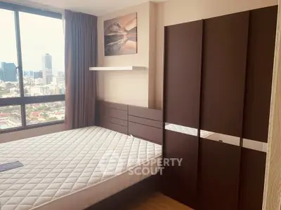 Modern bedroom with city view, featuring a large window and stylish furniture.