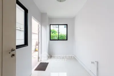 Bright empty room with white walls and large window overlooking greenery.