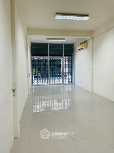 Spacious commercial space with glossy tiled flooring and large glass entrance, ideal for retail or office use.