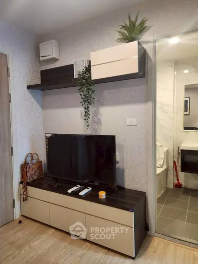 Modern living room with TV, stylish shelves, and bathroom view, perfect for urban living.