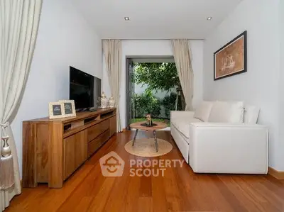 Stylish living room with wooden flooring, modern furniture, and garden view.
