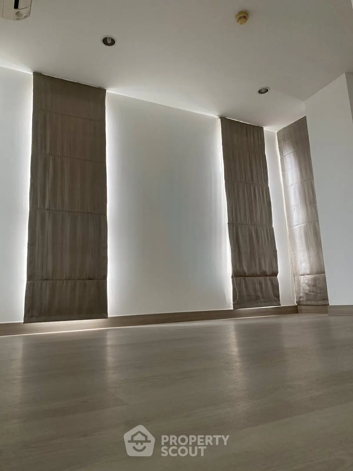 Spacious modern interior with elegant floor-to-ceiling curtains and sleek flooring, perfect for contemporary living.