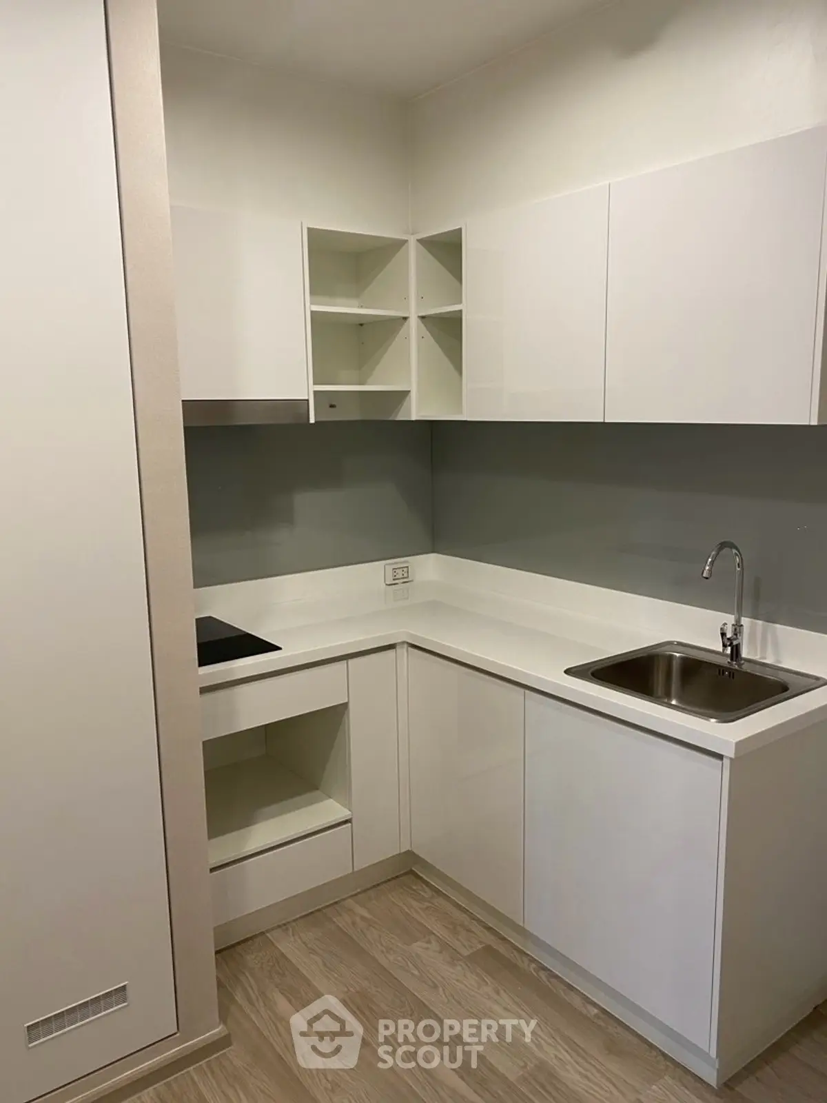 Modern compact kitchen with sleek white cabinets and integrated appliances