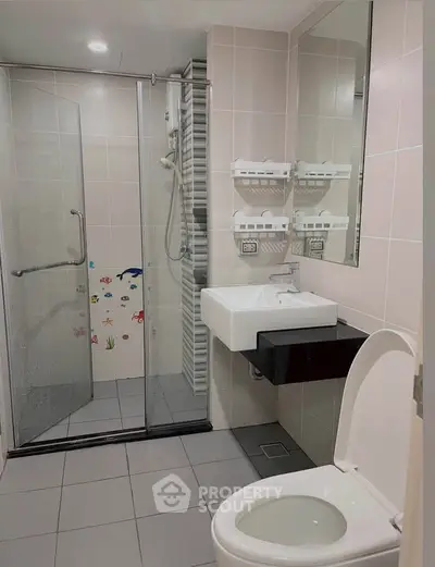 Modern bathroom with glass shower, sleek sink, and neutral tiles.