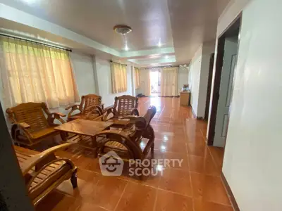 Spacious living room with wooden furniture and large windows for natural light.
