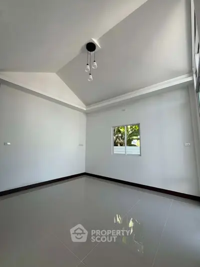 Spacious empty room with high ceiling and modern lighting, perfect for customization.