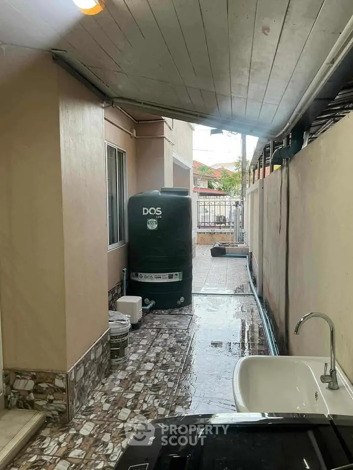 Charming outdoor utility area with sink and water tank, perfect for practical home maintenance.